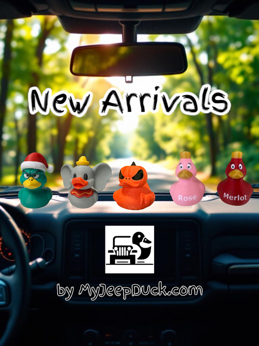 A cheerful collection of new Jeep ducks, including a Grumpy Green Christmas Duck, Flying Elephant Duck, Pumpkin Duck, and Wine Ducks, all displayed on a Jeep dashboard.